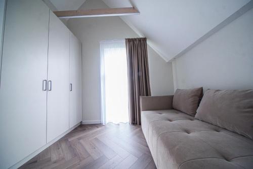 a living room with a couch and a window at Apartamentai Ieva Kunigiškėse in Palanga