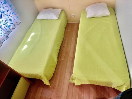 two beds in a room with yellow sheets at Bumgalow 5X in Pataias