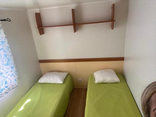 Kleines Zimmer mit zwei grünen Betten. in der Unterkunft Bumgalow 5X in Pataias