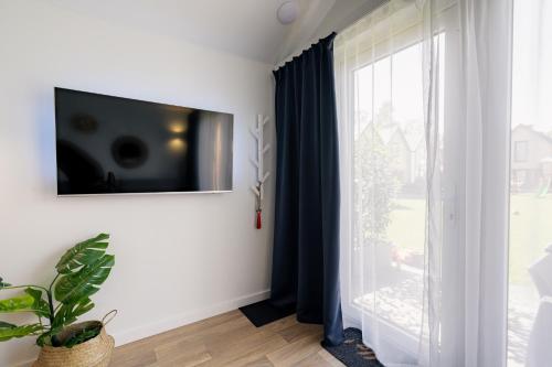 a living room with a tv on the wall next to a window at Holiday Point in Międzywodzie
