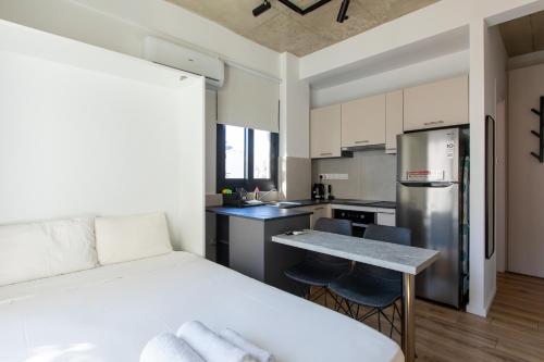 a bedroom with a white bed and a kitchen at YAMAS Urban LIving Spiridonos in Limassol