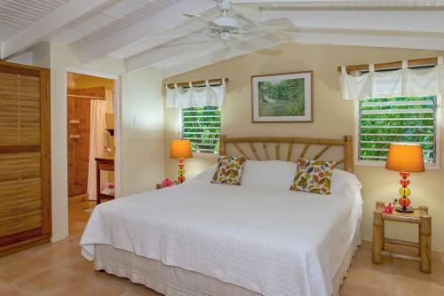 a bedroom with a white bed and two windows at Sunny Vacation Villa No 8 in Mandeville