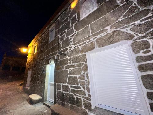 un edificio de piedra con puerta de garaje por la noche en CASA Outeiro 4 en Muros