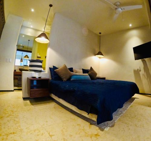 a bedroom with a bed with blue sheets and a table at Lively condo in Zihua! in Zihuatanejo