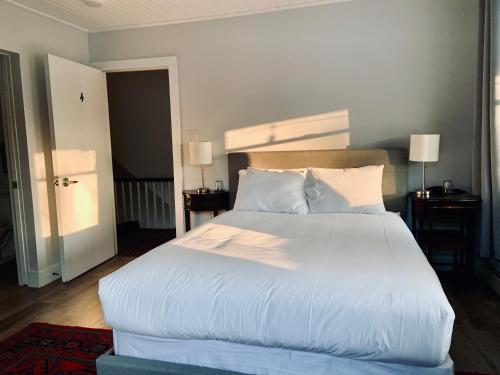 a bedroom with a large bed with white sheets and pillows at South Landing Inn in Niagara-on-the-Lake