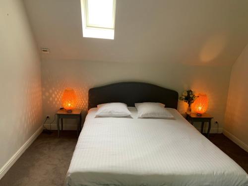une chambre avec un grand lit blanc avec deux lampes dans l'établissement Maison de Village Vexin site classé 1h Paris et Normandie grand jardin, à Reilly