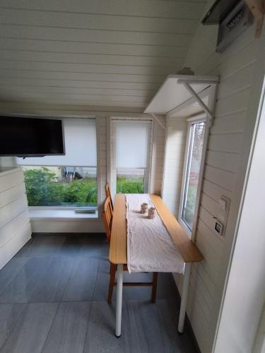 a dining room with a table and two windows at Guest House in the Garden in Hokksund