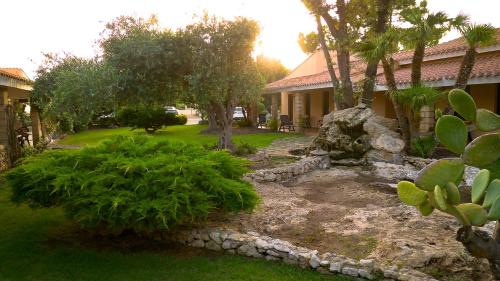 a yard with trees and a house with a rock garden at Sa Pedrera Country Hotel in Càbras