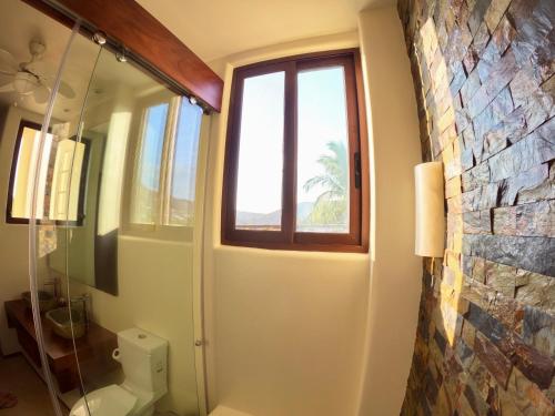 a bathroom with a window and a stone wall at Boutique Condo Close to Everything in Zihuatanejo