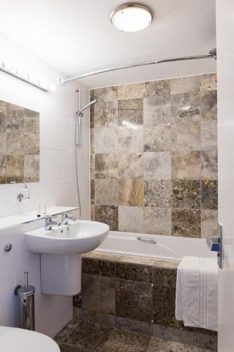 a bathroom with a sink and a tub and a toilet at The Beach Hotel in Minehead