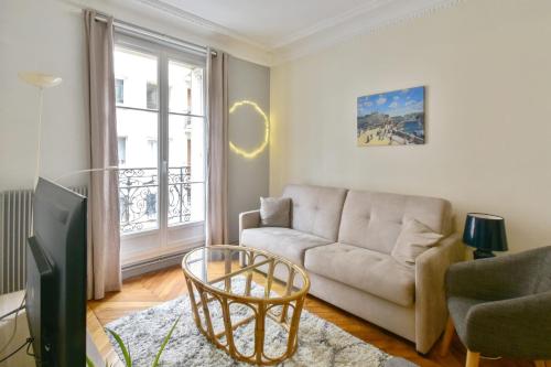 un salon avec un canapé et une fenêtre dans l'établissement Appartement Haussman et son balcon - Welkeys, à Paris