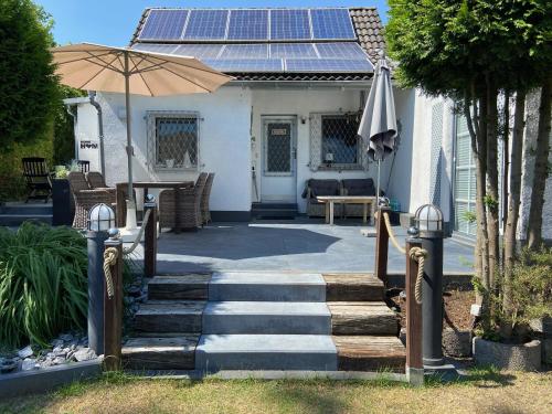 ein Haus mit einer Terrasse mit einem Sonnenschirm und einem Tisch in der Unterkunft Casaverde Koeln in Rösrath