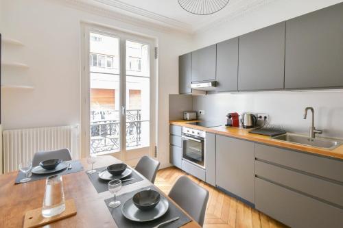 une cuisine avec une table, des chaises et un évier dans l'établissement Appartement Haussman et son balcon - Welkeys, à Paris