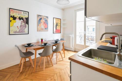 une cuisine avec une table, des chaises et un évier dans l'établissement Appartement Haussman et son balcon - Welkeys, à Paris