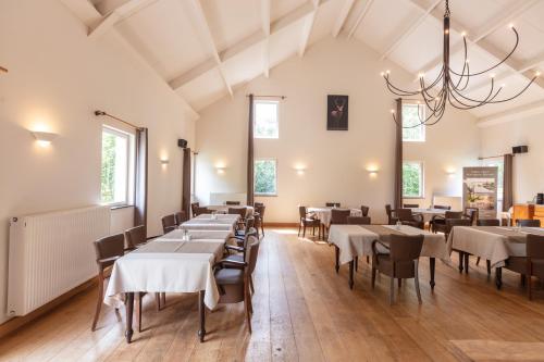 B&B Het Eycken Huys في التر: غرفة طعام بها طاولات وكراسي وثريا