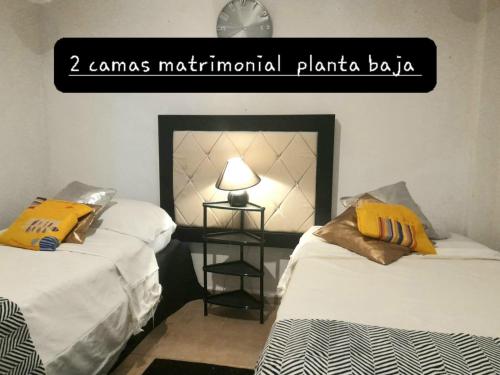 2 camas en una habitación con un cartel que dice "jamesmetual plantation" en casa habitacion el molino, en Tehuacán