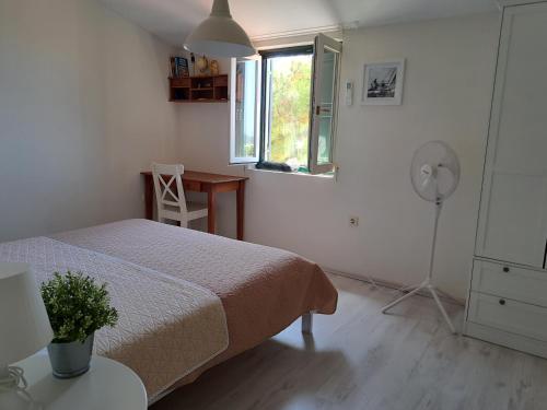 a bedroom with a bed and a desk and a window at Holiday home Voga in Maslinica
