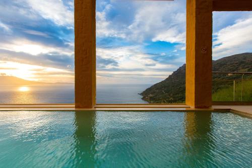 a swimming pool with a view of the ocean at Athina Epavlis - Ethereal Charm of Blue Horizons in Ravdhoúkha