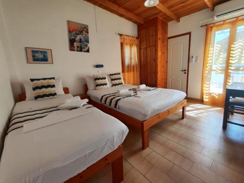 a bedroom with two beds and a table and a window at Oleander's Garden Traditional Cretan Cottage in Ferma