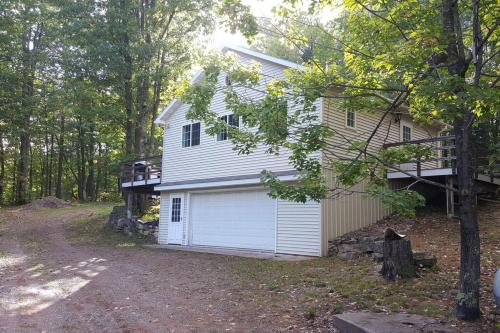 ein weißes Haus mit einer Garage im Wald in der Unterkunft MLR - Lakeview Cabin 