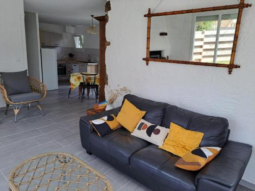 - un salon avec un canapé en cuir noir et des oreillers jaunes dans l'établissement Maison Biscarrosse plage 500m de l océan, à Biscarrosse