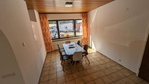 ein Esszimmer mit einem Tisch, Stühlen und einem Fenster in der Unterkunft FeWo Sonnenschein Bungalow in Sankt Ingbert