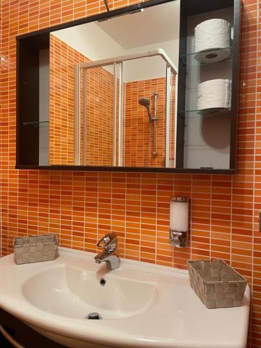 een wastafel in de badkamer met een oranje tegelmuur bij Varenna by Foot (no Taxi / Car needed) in Varenna