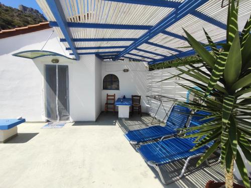 a patio with blue chairs and a palm tree at Oleander's Garden Traditional Cretan Cottage in Ferma