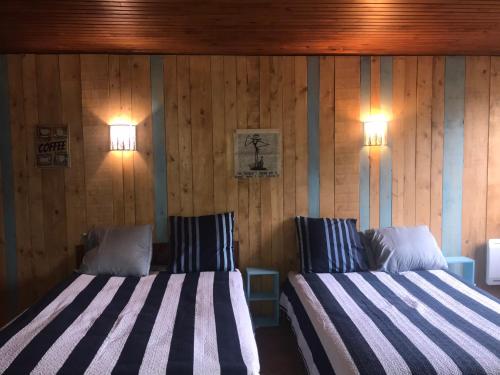 two beds in a room with wooden walls at Le refuge du berger in Choux