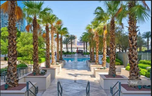 a row of palm trees in a courtyard with a pool at Signature MGM Suite with Strip and Sphere View in Las Vegas