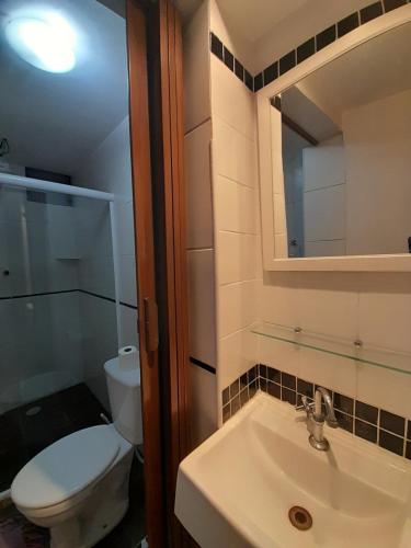 Un baño con inodoro, lavabo y espejo. en Albergue Rio Vermelho, en Salvador