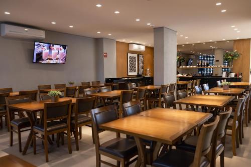 ein Restaurant mit Holztischen und -stühlen sowie einem Flachbild-TV in der Unterkunft Morada Inn Hotel in Franca