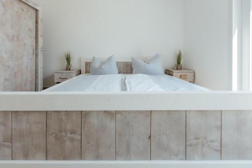 a white bedroom with a large bed with white sheets and pillows at Exklusive Ferienwohnungen an der Havel in Werder