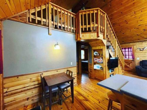 una habitación con una mesa y una escalera en una cabaña en The Loft at Bear Mountain log cabins, en Eureka Springs