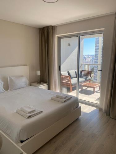 a bedroom with a large bed and a balcony at Elite Residense a 150 mts Praia da Rocha in Portimão