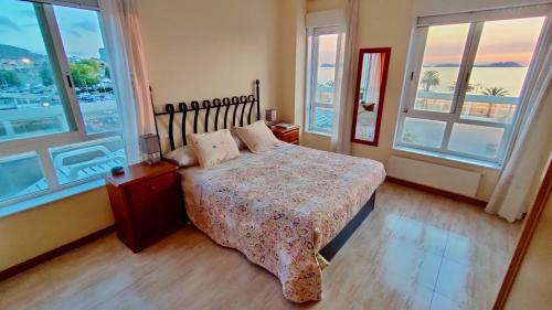 a bedroom with a bed and two windows at Samil Apartment, primera línea de playa con Wifi y Garaje in Vigo