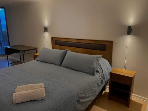 una camera da letto con un letto grande con testiera in legno di Hermoso y moderno departamento a pasos del lago a Puerto Varas