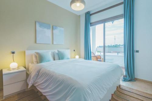um quarto branco com uma cama grande e uma janela grande em lovely 2 bedroom vacation home with pool/beach em Skhirat