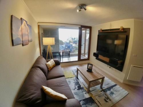 un soggiorno con divano e TV a schermo piatto di Hermoso y moderno departamento a pasos del lago a Puerto Varas