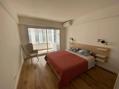 een slaapkamer met een bed, een stoel en een raam bij Renovated 4 room Apartment-Parking next door and Beach at 700m in Antibes
