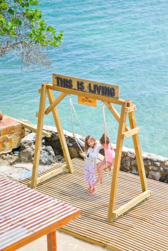 two little girls sitting in a swing on the beach at Hotel Isla Del Pirata in Isla del Pirata