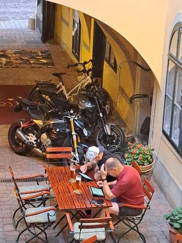 a man sitting at a table next to a motorcycle at Hotel Wollner in Sopron