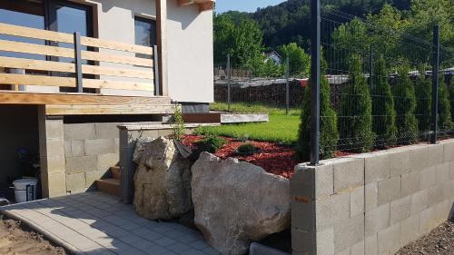 a house with a retaining wall and a fence at Apartmány pod Janovským vŕškom in Plavecký Svätý Mikuláš