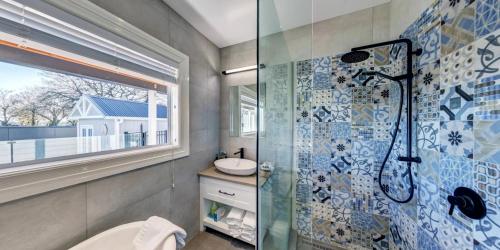 a bathroom with a glass shower and a sink at AristaAir- Poppies Luxury Villa in Rotorua