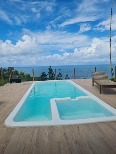 a swimming pool on a deck with the ocean in the background at Village as casinhas in Uruçuca