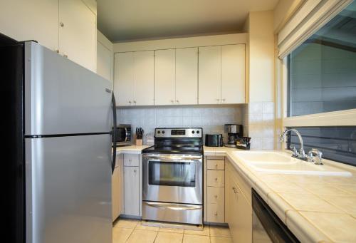 a kitchen with white cabinets and a stainless steel refrigerator at Kapalua Villas Maui - Select Your Unit in Kahana