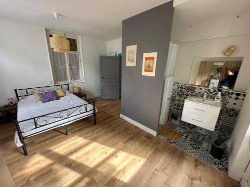 een slaapkamer met een bed en een houten vloer bij Appartement avec jardin Villeveque 