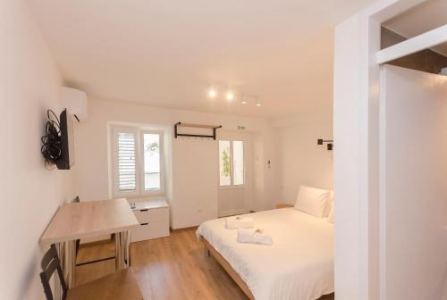 ein weißes Schlafzimmer mit einem Bett und einem Schreibtisch in der Unterkunft Apartments Villa Vista Sol in Vodice