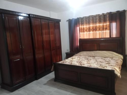 a bedroom with a bed and wooden cabinets at فيلا بوابة جرش الرومانيه الشماليه in Jerash