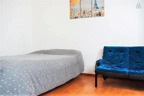 uma cama e uma cadeira azul num quarto em Gorriti 3744 Pet & 420 Friendly em Buenos Aires